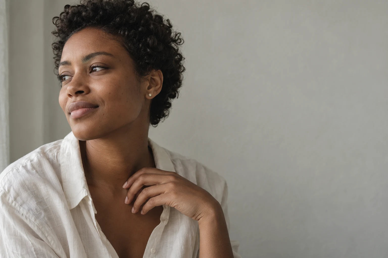 A woman wearing delicate jewelry with an ivory shirt