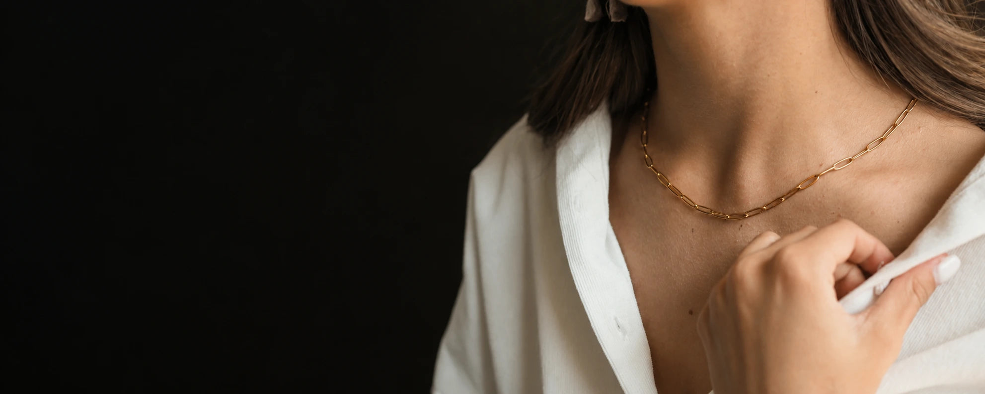 A delicate gold necklace worn with an ivory blouse in natural light